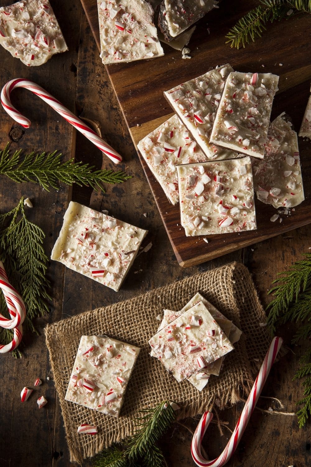 Peppermint bark on a cutting board with candy canes.