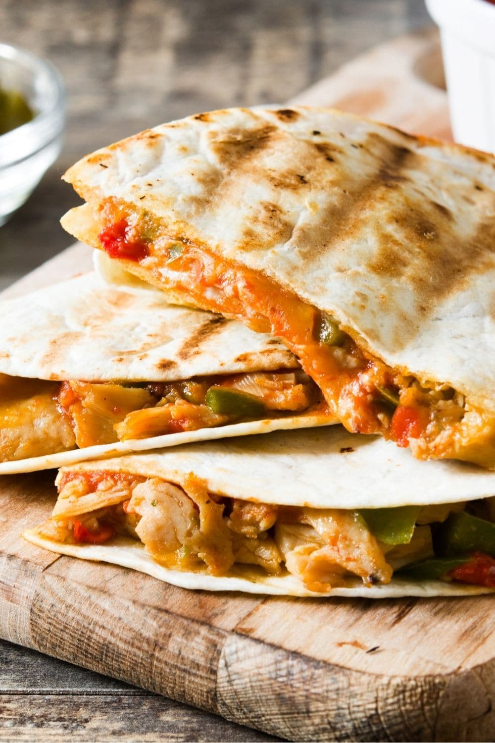 Tortillas with chicken, bell peppers and cheese filling, stacked on top of each other on a wooden board