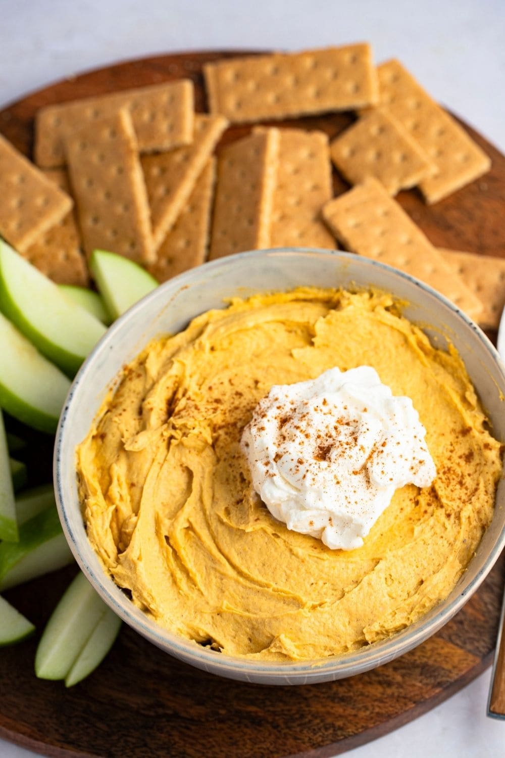 Pumpkin Fluff Dip on a bowl with whipped cream on top served with crackers. 