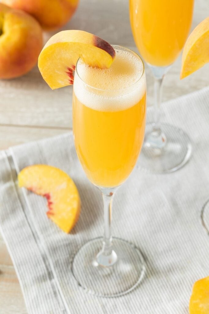 Peach Bellini Mimosas with Champagne in Flute Glasses Garnished with Peach Slices