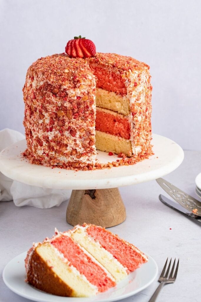 Sweet Strawberry Crunch Cake on a cake stand with one slice removed