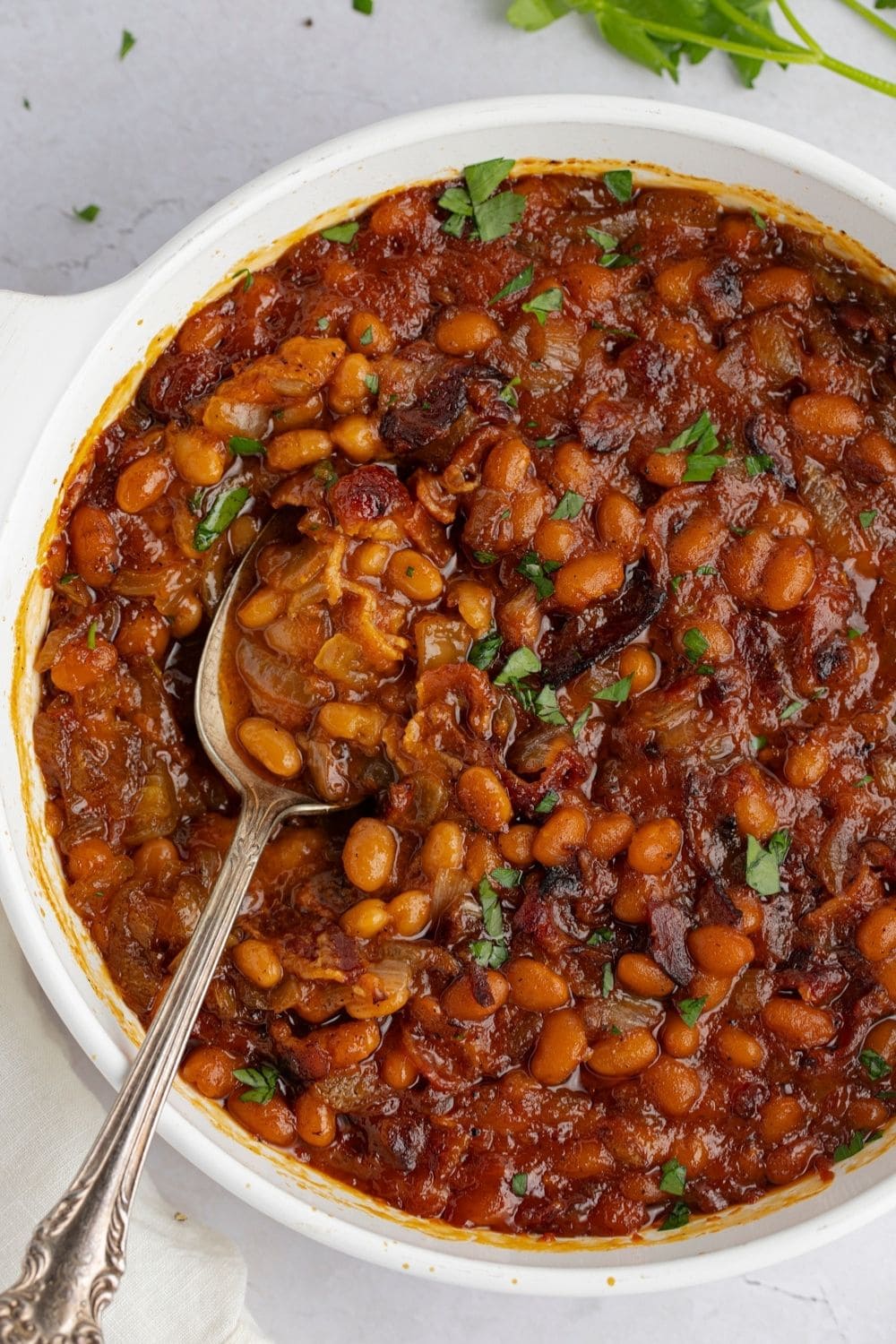 Baked beans in BBQ sauce on a white bowl. 