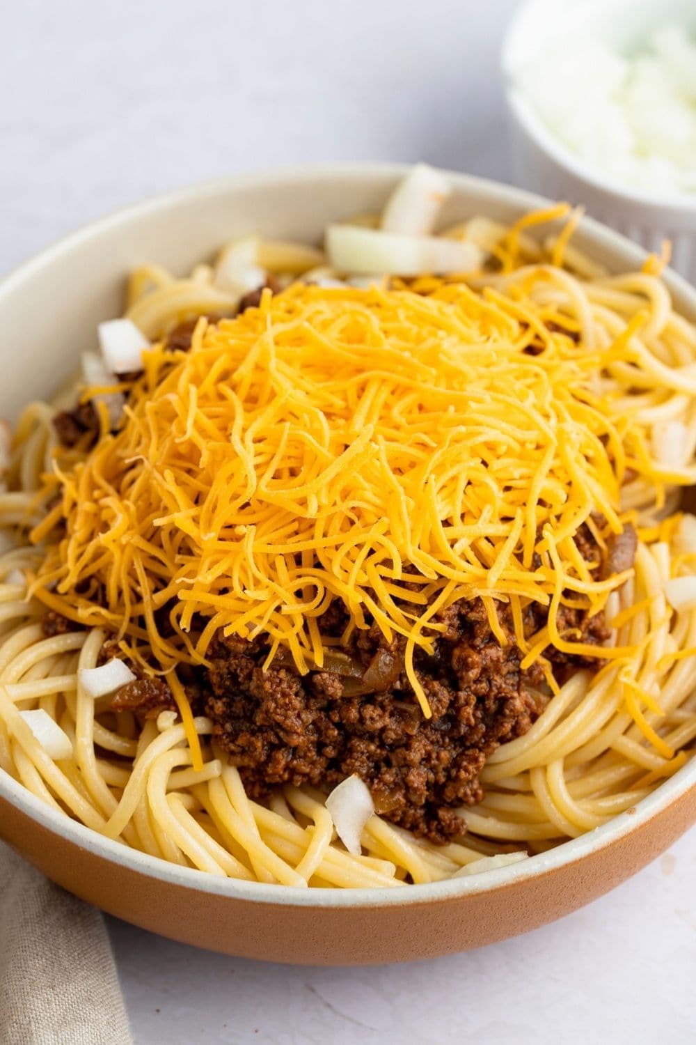 Copycat Skyline Chili in a Bowl with cheese and spaghetti. 