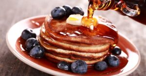 A Stack of Pancakes with Bananas, Blueberries and Maple Syrup