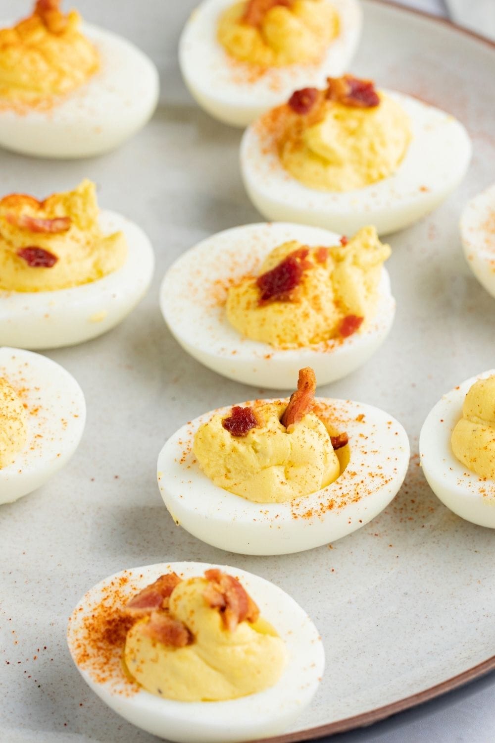 Deviled eggs topped with bacon and paprika.