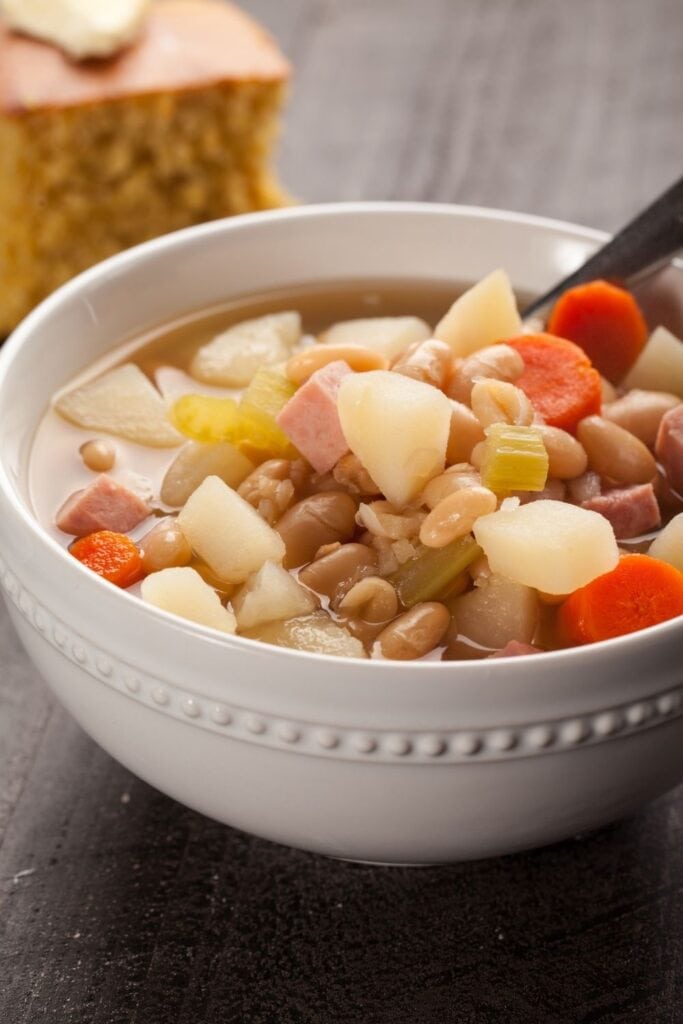 Ham and Bean Soup with Carrots in a Bowl served with cornbread on the side