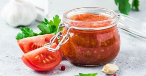 Homemade Canned Tomato Sauce in a Glass Jar with Fresh Tomatoes