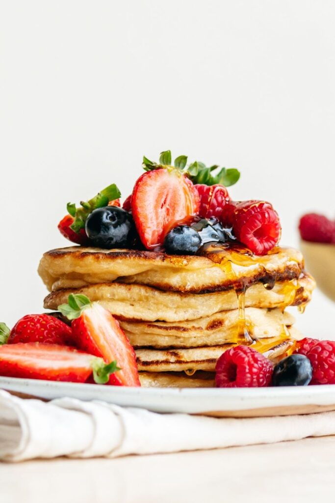 Easy Sourdough Discard recipes featuring sourdough discard pancakes with berries and syrup stacked on a plate.