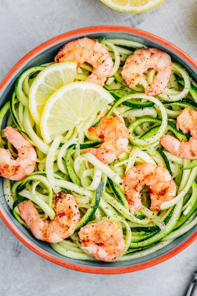 25 Easy Spiralizer recipes that go beyond zoodles. Photo shows Zucchini Noodles with Shrimp and Lemons in a bowl.