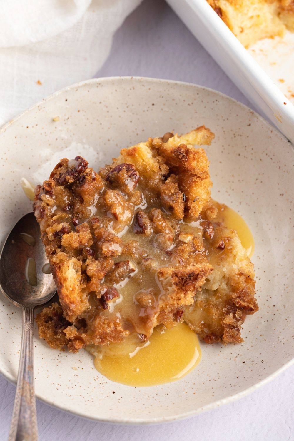 The Best Paula Deen Bread Pudding (Copycat) featuring Bread Pudding Loaded with Sweet Custard and Butter in a Dish with a Spoon