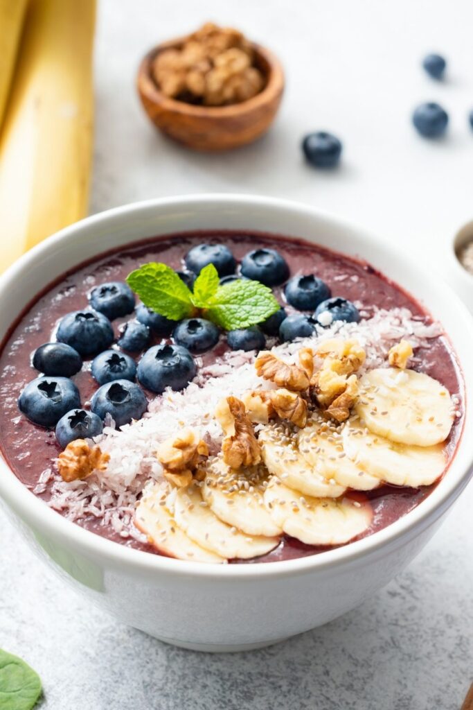 Easy Breakfast Ideas for Kids featuring Homemade Acai Smoothie Bowl with Bananas and Blueberries served in a bowl with coconut and fresh mint