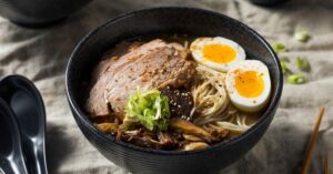 Homemade Japanese Pork Ramen with Eggs and Mushrooms in a Black Bowl