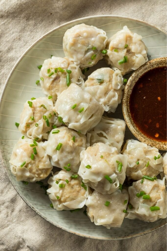 25 Easy Dumpling Recipes That Go Beyond Potstickers including Homemade Pork Shu Mai Dumplings with Sauce served on a plate