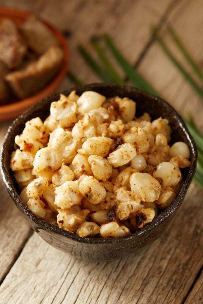 30 Hominy Recipes You Never Knew You Needed including Hominy and Pork Rind in a Black Bowl