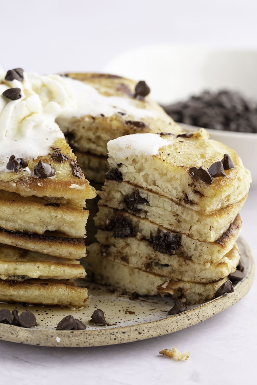 Sliced chocolate chip pancakes with whipped cream on top.   