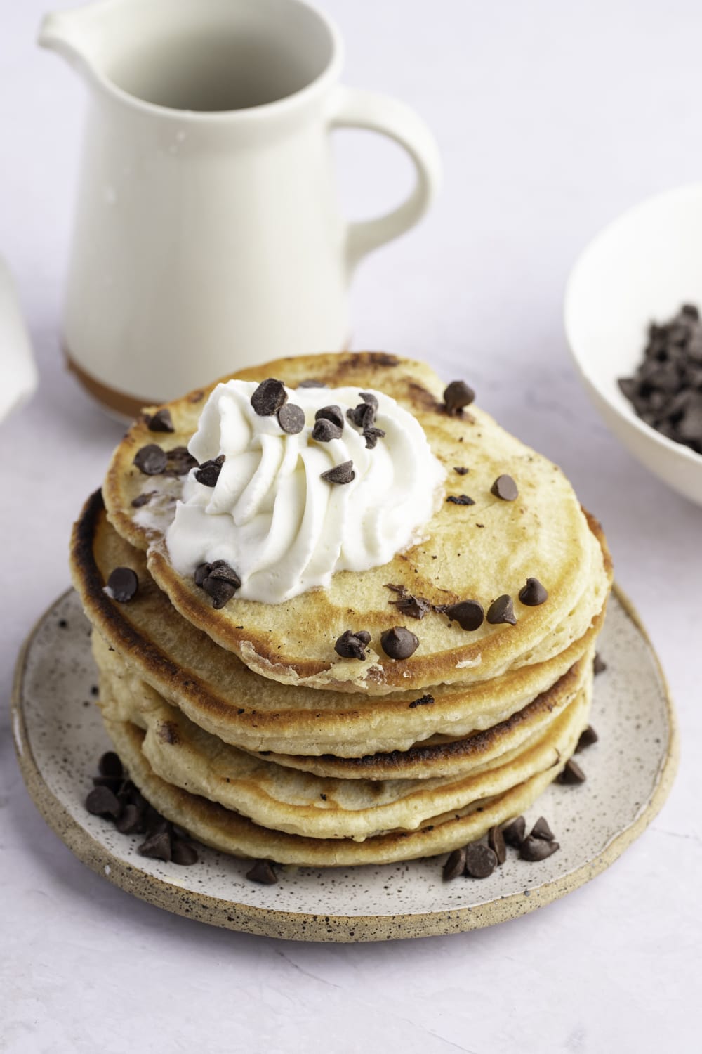 Chocolate Chip Pancakes Stacked on a Plate With Whip Cream on Top