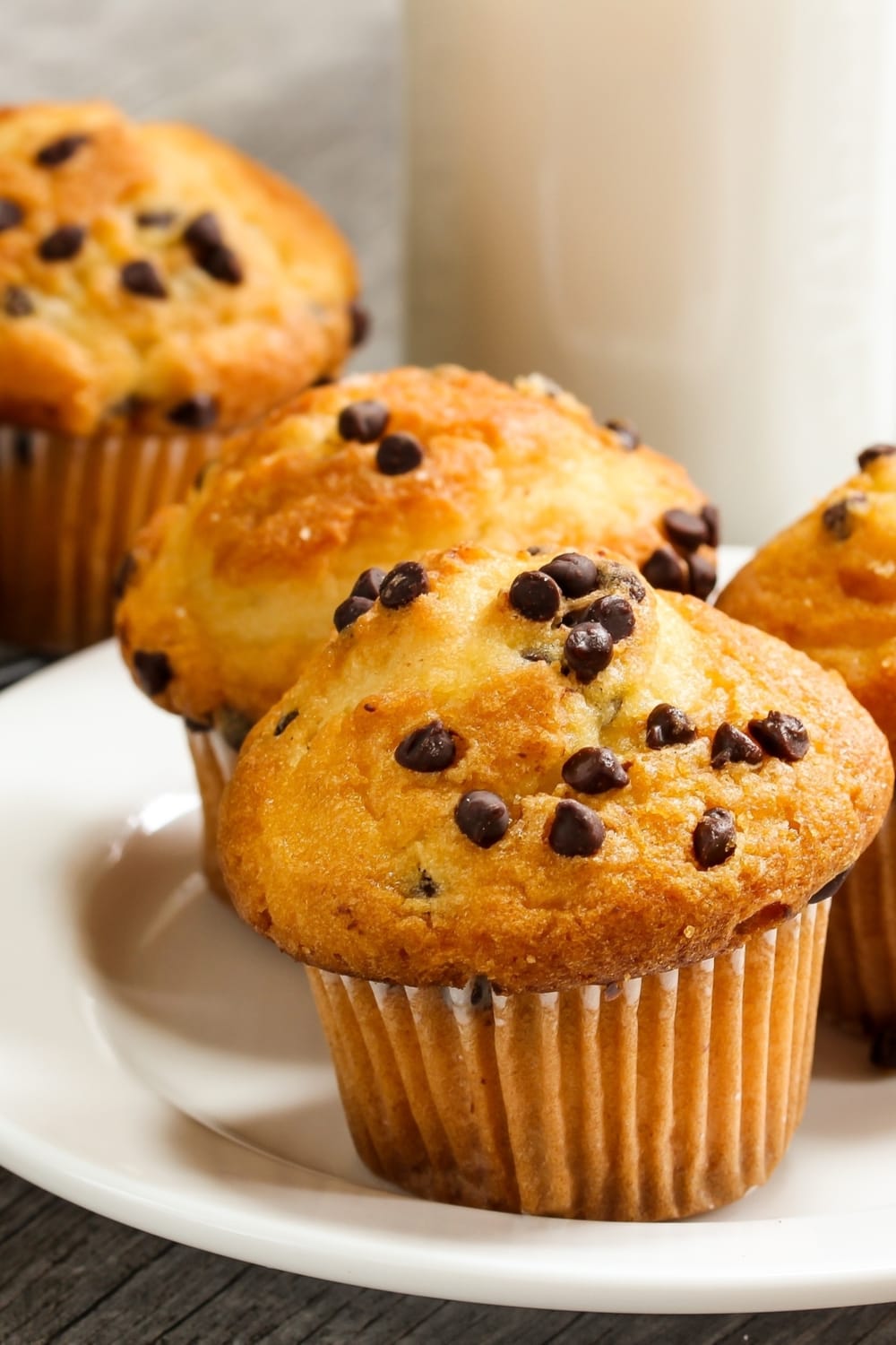 Chocolate Chip Muffins with a glass of milk in the background.