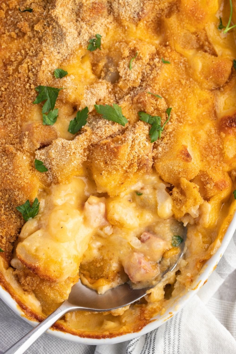Spoon Digging Into Ham and Potato Casserole with Herbs