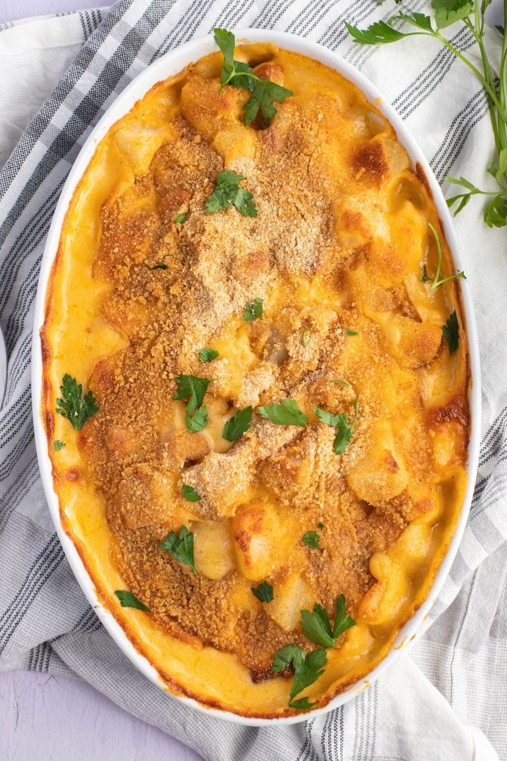 Hearty and Creamy Ham and Potato Casserole in an Oval Casserole Dish on a Plaid Table Cloth