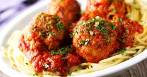 Spaghetti and Meatballs with Herbs in a White Plate