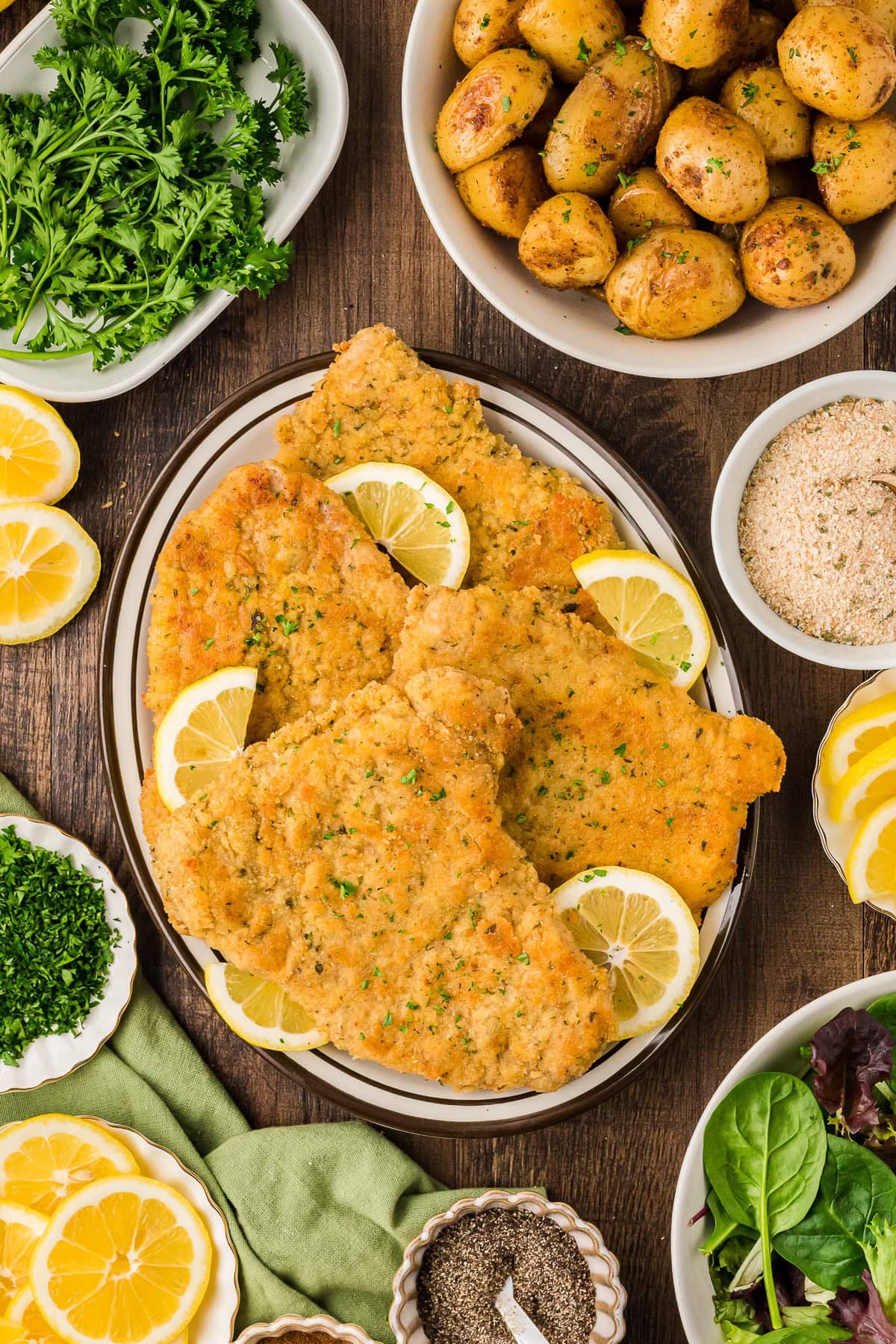 An overhead view of Wiener Schnitzel with lemon wedges in a platter