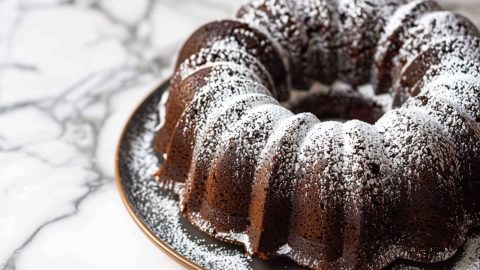 Too Much Chocolate Cake Bundt on a Serving Plate on a White Marble Table