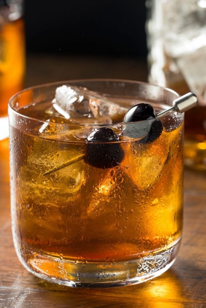 Best Averna Cocktails Featuring Black Manhattan Over Ice With Black Cherry Garnish