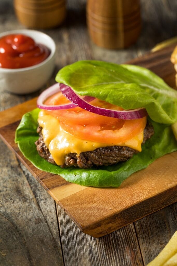 23 Best Keto Burger Recipes featuring Homemade Burger Wrapped In Lettuce with Tomatoes and Onions