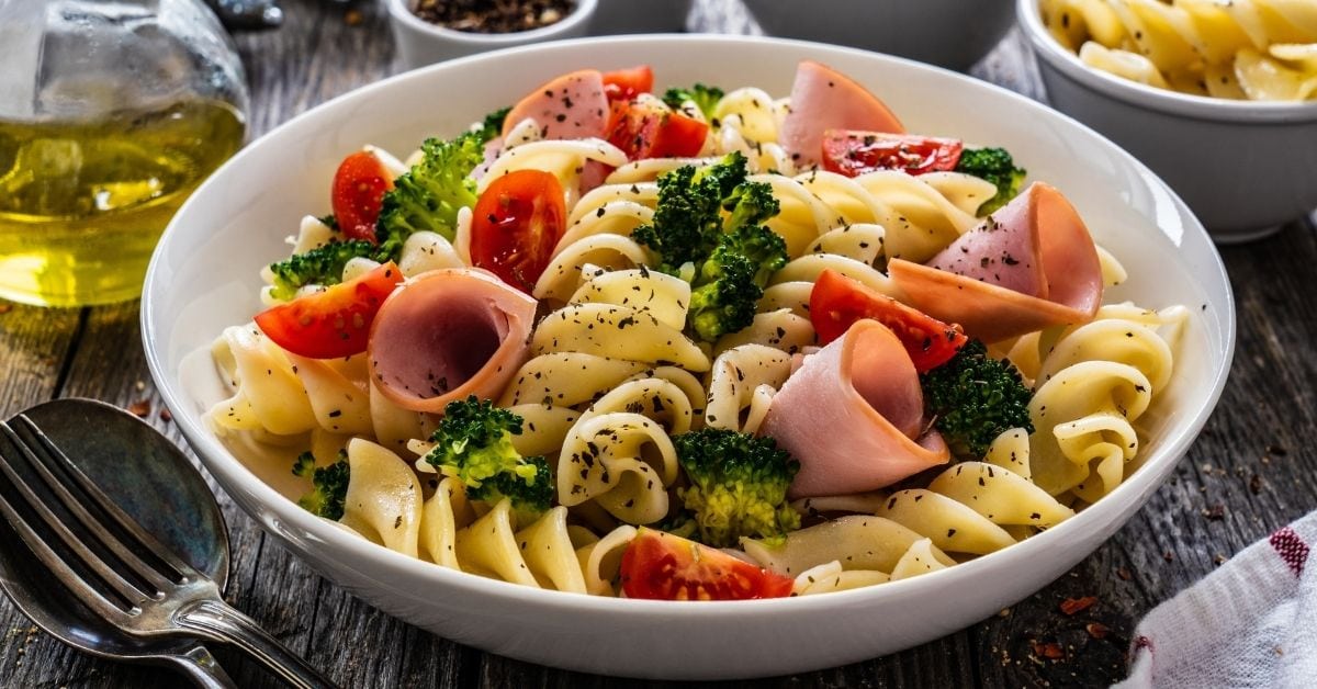 Homemade Ham and Broccoli Pasta with Tomatoes in a White Bowl