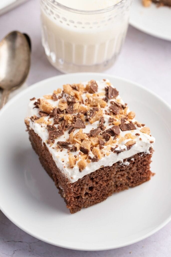 Slice of Heath Bar Cake served on a plate with a glass of milk
