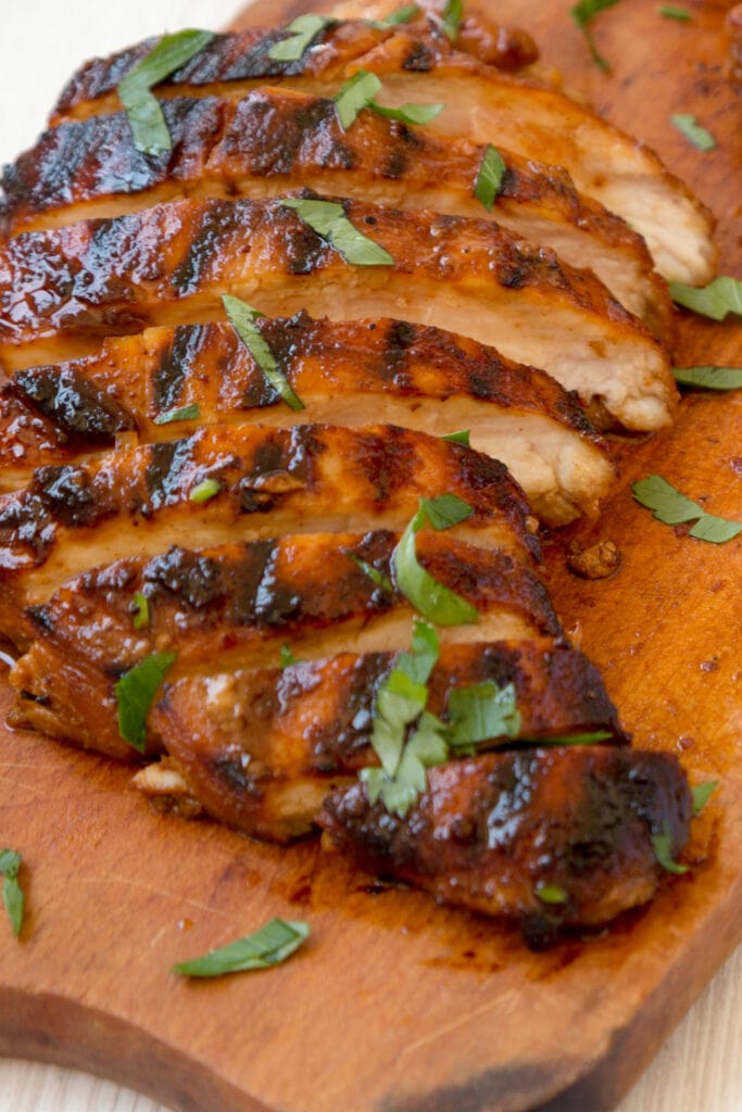 Sliced Chipotle Chicken on a Cutting Board with Fresh Herbs