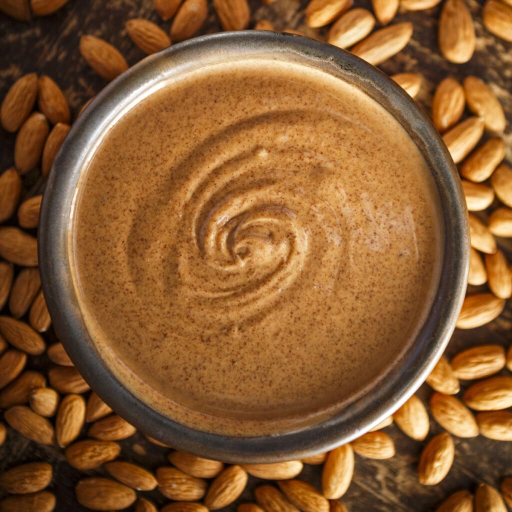 Almond Butter in a jar surrounded by nuts