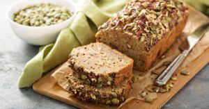 Homemade Paleo Banana Bread with Seeds and Nuts in a Wooden Cutting Board