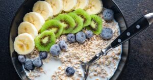 Homemade Paleo Breakfast Porridge with Oatmeal, Bananas, Kiwi and Blueberries