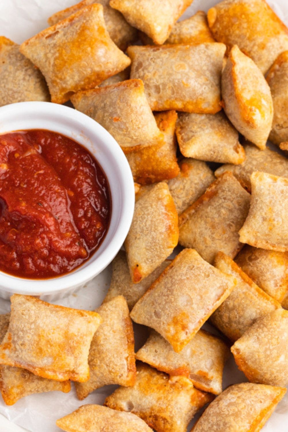 A bunch of pizza rolls served with marinara sauce.