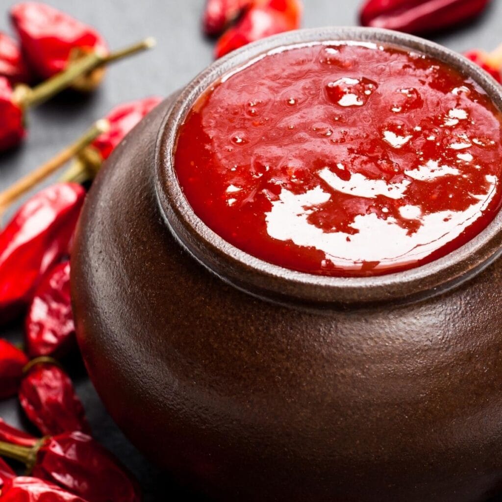 Ketchup in a Small Brown Pot Surrounded by Cayenne