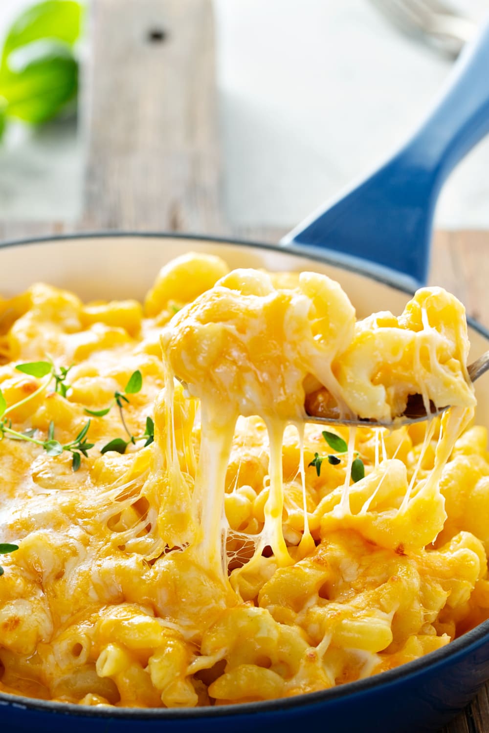 Spoon scooping cheesy and gooey mac and cheese on a pot.