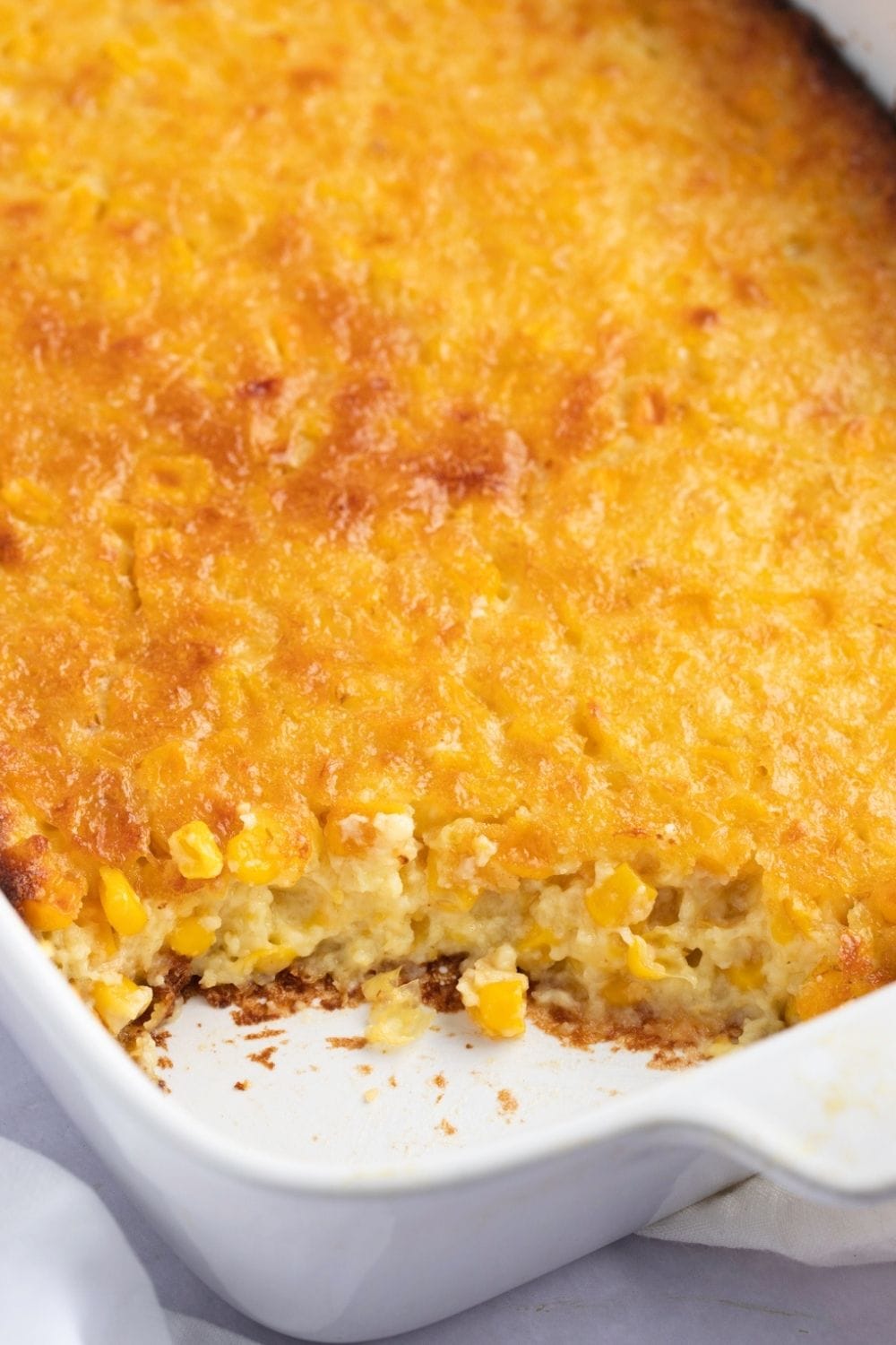 Portion missing corn pudding on a casserole dish.