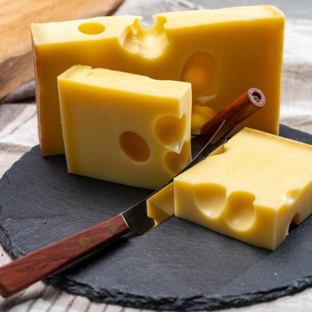 Sliced Emmental Cheese On A Black Chopping Board