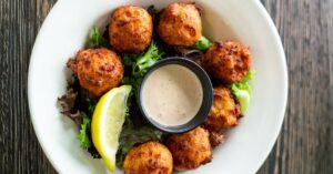 Homemade Conch Fritters with Greens, Lemons and Dipping Sauce