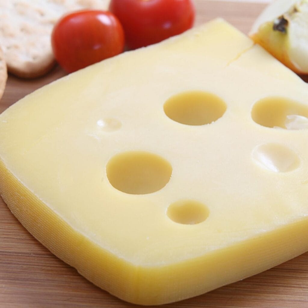 Jarlsberg Cheese Sliced on Top of a Wooden Table