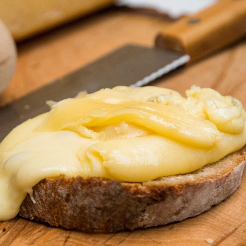 Melted Raclette Cheese On Top Of A Slice Of Bread