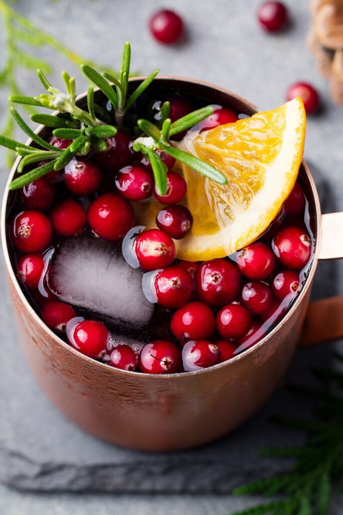 Cold Moscow Mule with Cranberries, an Orange Wedge, and Rosemary