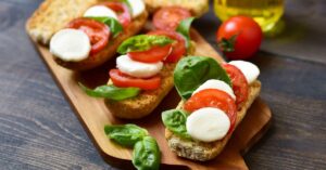 Homemade Caprese Crostini with Mozzarella and Tomatoes in a Wooden Chopping Board
