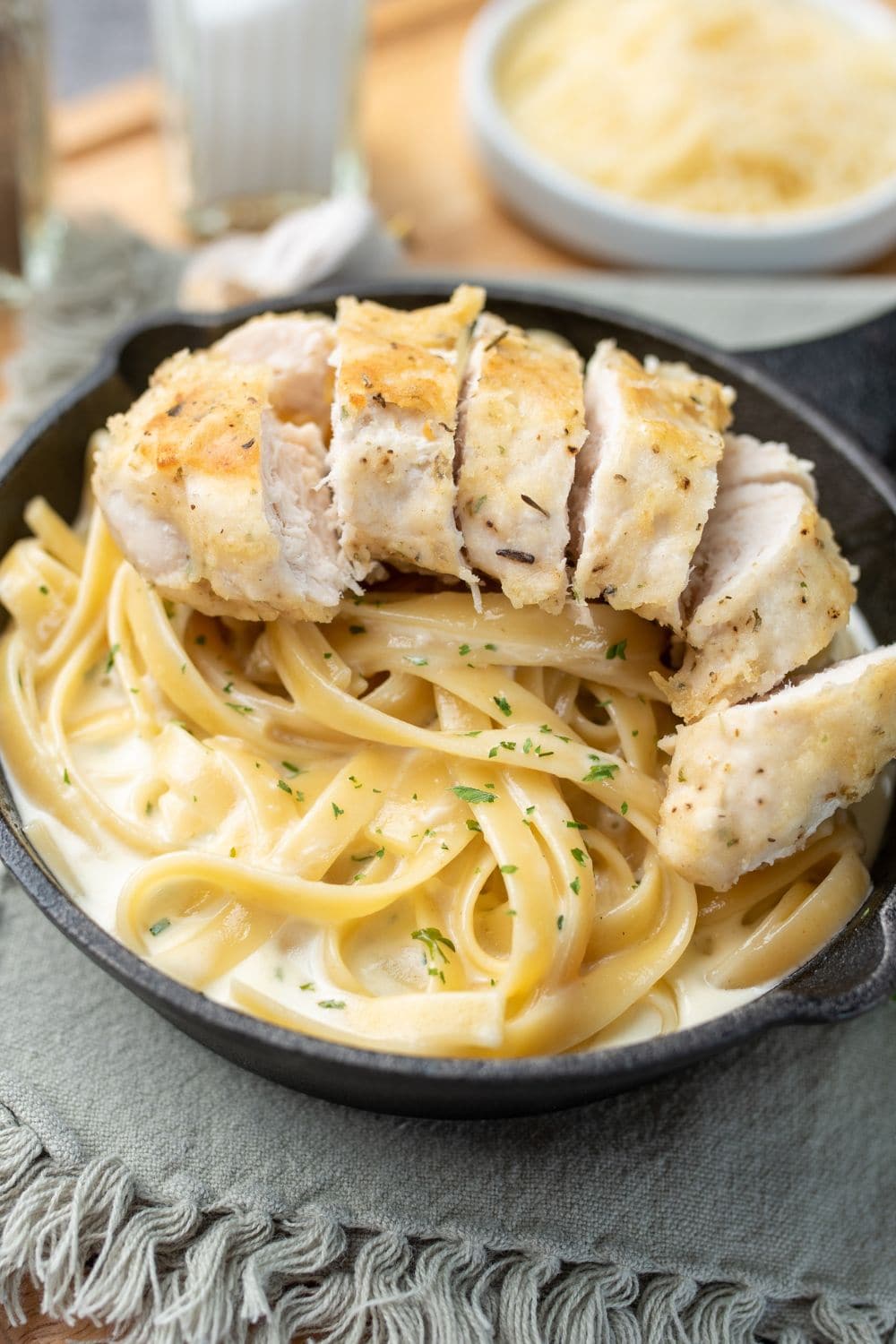 A bowl of creamy fettuccine alfredo with chicken strips on top.