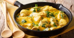 Homemade Spicy Chicken Coconut Curry with Herbs in a Skillet