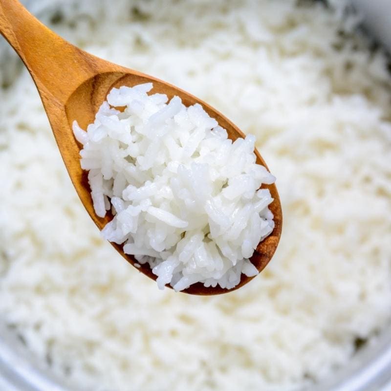 How to Reheat Leftover Rice (3 Simple Ways): Cooked White Rice Scooped With A Wooden Spoon