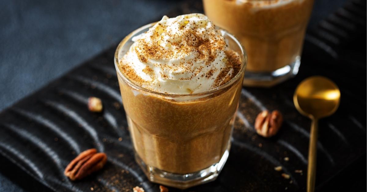 A Glass of Pumpkin Spice Latte with Whipped Cream, Cinnamon and Pecan Nuts