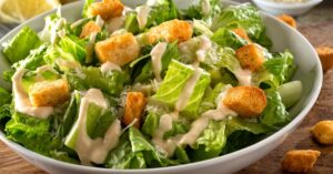 Healthy Homemade Caesar Salad with Croutons and Dressing in a White Bowl