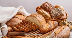 Mixed Breads in Basket and Wooden Cutting Board